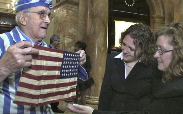 In this Nov. 11, 2012, still image from the film "Etched in Glass: The Legacy of Steve Ross," provided by Many Hats Productions, Holocaust survivor Steve Ross, from left, displays an American flag to Brenda Sattler and Gwen Sattler Allanson at a Veteran's Day event at the Statehouse in Boston. (Tony Bennis/Many Hats Productions via AP) In this Nov. 11, 2012, still image from the film "Etched in Glass: The Legacy of Steve Ross," provided by Many Hats Productions, Holocaust survivor Steve Ross, from left, displays an American flag to Brenda Sattler and Gwen Sattler Allanson at a Veteran's Day event at the Statehouse in Boston. (Tony Bennis/Many Hats Productions via AP)