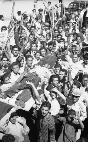 In this Aug. 19, 1953 file photo, the body of a man killed in a pro-Shah riot which swept through Tehran is carried aloft by demonstrators. (AP Photo/Aziz Rashki, File)