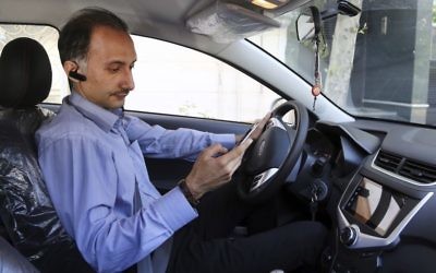 In this Monday, May 23, 2017, photo, Mostafa Meisami, driver of the Snapp online taxi company works with his smartphone in his car in Tehran, Iran. (AP Photo/Ebrahim Noroozi)