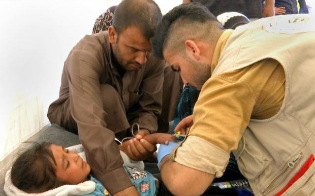 In this screen grab from video, a man comforts his daughter as a doctor treats her after she was taken ill with suspected food poisoning in the Hassan Sham U2 camp for displaced people east of Mosul, Iraq, June 13, 2017. (AP/Balint Szlanko) In this screen grab from video, a man comforts his daughter as a doctor treats her after she was taken ill with suspected food poisoning in the Hassan Sham U2 camp for displaced people east of Mosul, Iraq, June 13, 2017. (AP/Balint Szlanko)