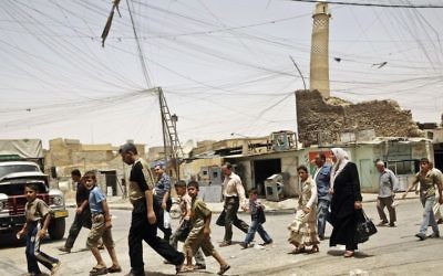 Residents walk past the crooked minaret of the iconic al-Nuri mosque in Mosul, Iraq, June 8, 2009. (AP Photo/Maya Alleruzzo, File)