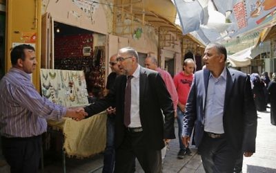 In this Monday, June 5, 2017 photo, the Mayor of Hebron Tayseer Abu Sneineh greets a shopkeeper at a market in the West Bank city of Hebron. (AP Photo/Nasser Shiyoukhi)