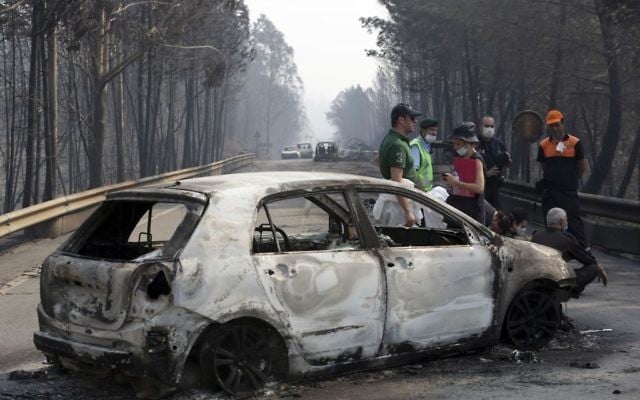 Police investigators stand by a burnt car on the road between Castanheira de Pera and Figueiro dos Vinhos, central Portugal, June 18 2017. (AP/Armando Franca) Police investigators stand by a burnt car on the road between Castanheira de Pera and Figueiro dos Vinhos, central Portugal, June 18 2017. (AP/Armando Franca)