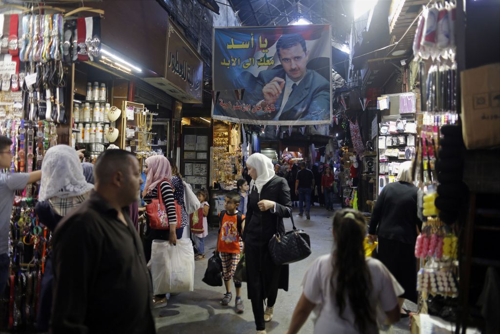 In this May 18, 2017 photo, Syrians shop under a banner showing President Bashar Assad at the Hamadiyah market, in the Old City of Damascus, Syria. (AP Photo/Hassan Ammar) In this May 18, 2017 photo, Syrians shop under a banner showing President Bashar Assad at the Hamadiyah market, in the Old City of Damascus, Syria. (AP Photo/Hassan Ammar)