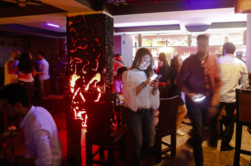 In this May 18, 2017. photo, a Syrian checks her mobile as others dance at a popular bar in the Old City in Damascus, Syria, (AP Photo/Hassan Ammar) In this May 18, 2017. photo, a Syrian checks her mobile as others dance at a popular bar in the Old City in Damascus, Syria, (AP Photo/Hassan Ammar)
