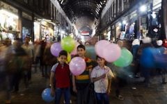In this May 18, 2017, photo, Syrian boys pose for a picture as they sell balloons at the Hamadiyah market, in the Old City of Damascus, Syria. (AP Photo/Hassan Ammar)