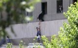 Iranian policemen evacuate a child from the parliament building in Tehran during a terror attack, June 7, 2017. (AFP PHOTO / FARS NEWS / OMID VAHABZADEH)