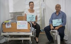 Shlomo Ben Dor (R) and Pazit Ben Israel sit at the protest tent of the Hadassah Hospital hemato-ontology department in Sacher Park, Jerusalem, wearing signs which say 'I'm on hunger strike,' June 25, 2017 (Yonatan Sindel/Flash90)