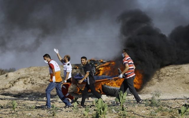 Palestinian protesters and medics carry a wounded man during clashes with Israeli security forces near the border fence east of Jabalia refugee camp on June 23, 2017. (AFP/MOHAMMED ABED) Palestinian protesters and medics carry a wounded man during clashes with Israeli security forces near the border fence east of Jabalia refugee camp on June 23, 2017. (AFP/MOHAMMED ABED)