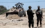 Security forces loyal to the Hamas terror group stand by as bulldozers clear an area for a large buffer zone on the border with Egypt in the southern Gaza strip town of Rafah, on June 28, 2017. (AFP/Said Khatib)