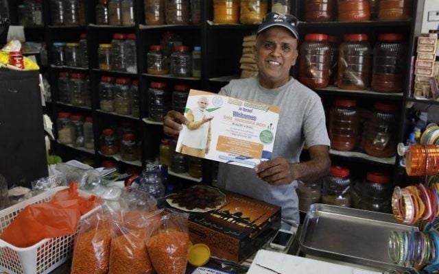Shaul Divekar, an Indian who emigrated to Israel as a child, holds a poster announcing the visit of the Indian prime minister to Israel at his Indian spice shop in the market of the small city of Ramla, south of Tel Aviv, on July 2, 2017. (AFP/ MENAHEM KAHANA) Shaul Divekar, an Indian who emigrated to Israel as a child, holds a poster announcing the visit of the Indian prime minister to Israel at his Indian spice shop in the market of the small city of Ramla, south of Tel Aviv, on July 2, 2017. (AFP/ MENAHEM KAHANA)