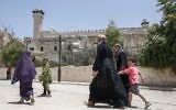 A picture taken on July 7, 2017 shows Palestinians walking by outside the Tomb of the Patriarchs in the West Bank city of Hebron. (AFP/Hazem Bader)
