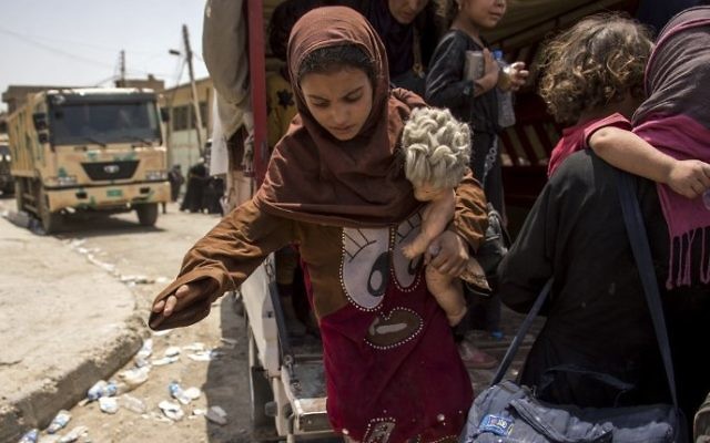 An Iraqi girl who fled the fighting between government forces and Islamic State (IS) group jihadists in the Old City of Mosul, holds a doll in her arm as she disembarks from a vehicle in the city's western industrial district on July 8, 2017 (AFP PHOTO / Fadel SENNA)