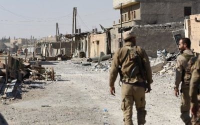 Members of the Syrian Democratic Forces (SDF), an alliance of Kurdish and Arab fighters, walk along a damaged street in eastern Raqqa, Syria, July 14, 2017. 
(AFP/Bulent Kilic)