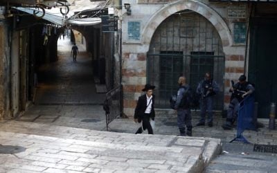 A Jewish ultra-Orthodox man walks past Israeli border policemen as they stand guard in Jerusalem's Old City, on July 16, 2017. (AFP PHOTO / Menahem KAHANA)