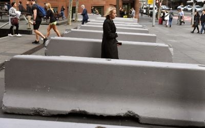 Pedestrians walk past newly-installed concrete security bollards near the Lindt Cafe on July 17, 2017, scene of the 2014 Sydney cafe seige, in which two hostages and the gunman were killed. (AFP/WILLIAM WEST)
