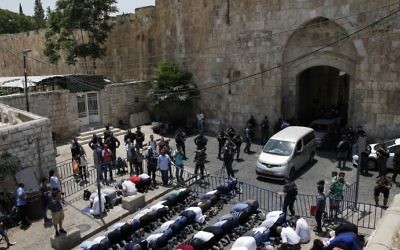 Muslim worshipers pray outside the Old City of Jerusalem's Lions Gate in protest of the placement of metal detectors at entrances to the Temple Mount on July 17, 2017. (AFP Photo/Ahmad Gharabli)