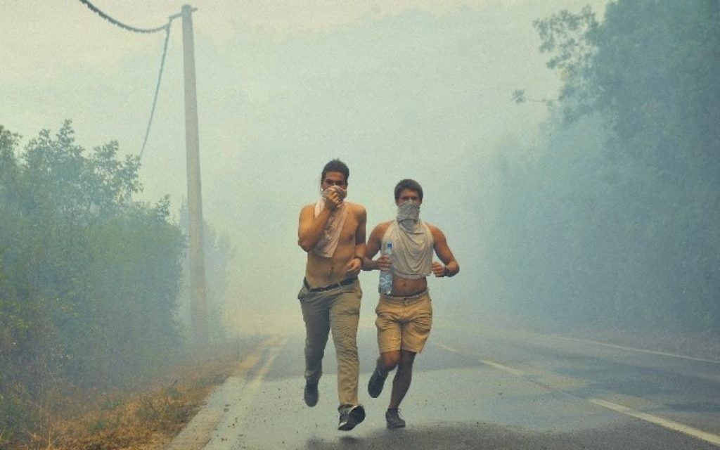 People run through smoke as a forest fire rages on the Lustica Peninsula near the town of Tivat in Montenegro on July 17, 2017. (AFP PHOTO / Savo PRELEVIC)