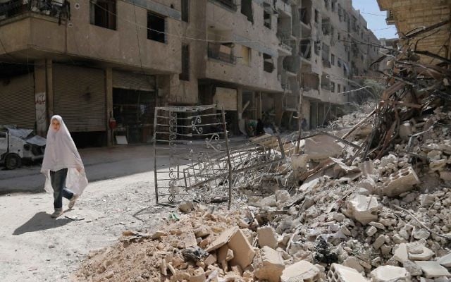 A girl walks past the rubble of a destroyed building down a street in the rebel-held Syrian town of Ayn Tarma, in the Ghouta area east of the capital Damascus, July 19, 2017. (AFP/ABDULMONAM EASSA) A girl walks past the rubble of a destroyed building down a street in the rebel-held Syrian town of Ayn Tarma, in the Ghouta area east of the capital Damascus, July 19, 2017. (AFP/ABDULMONAM EASSA)