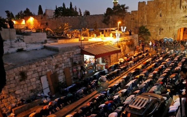 Palestinian Muslim worshippers pray next to Lions Gate, a main entrance to the Al-Aqsa Mosque compound in Jerusalem's Old City, on July 19, 2017, as they protest against new Israeli security measures implemented at the holy site (AFP PHOTO / AHMAD GHARABLI)