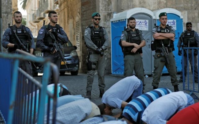 Israeli security forces stand guard in front of Palestinian Muslim worshipers praying outside Lions Gate, a main entrance to the Temple Mount compound in Jerusalem's Old City, on July 19, 2017(AFP PHOTO / Ahmad GHARABLI) Israeli security forces stand guard in front of Palestinian Muslim worshipers praying outside Lions Gate, a main entrance to the Temple Mount compound in Jerusalem's Old City, on July 19, 2017(AFP PHOTO / Ahmad GHARABLI)
