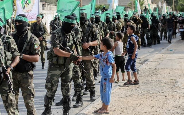 Palestinian children greet fighters from the Ezzedine al-Qassam Brigades, the armed wing of the Palestinian Hamas movement, march in the streets in the southern Gaza Strip city of Khan Yunis on July 20, 2017. / AFP PHOTO / SAID KHATIB Palestinian children greet fighters from the Ezzedine al-Qassam Brigades, the armed wing of the Palestinian Hamas movement, march in the streets in the southern Gaza Strip city of Khan Yunis on July 20, 2017. / AFP PHOTO / SAID KHATIB