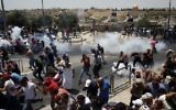 Palestinian worshipers run for cover from teargas, fired by Israeli  security forces, following prayers outside Jerusalem's Old City in front of the Al-Aqsa mosque compound on July 21, 2017. (AFP/Ahmad Gharabli)