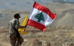 A member of the Hezbollah terror group holds Lebanese and Hezbollah flags during a press tour near the border town of Arsal on July 25, 2017. (AFP Photo/Stringer)