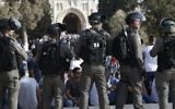 Israeli security forces stand before Palestinians on the Temple Mount in Jerusalem on July 27, 2017, with the Al-Aqsa mosque appearing in the background. (AFP PHOTO / AHMAD GHARABLI)