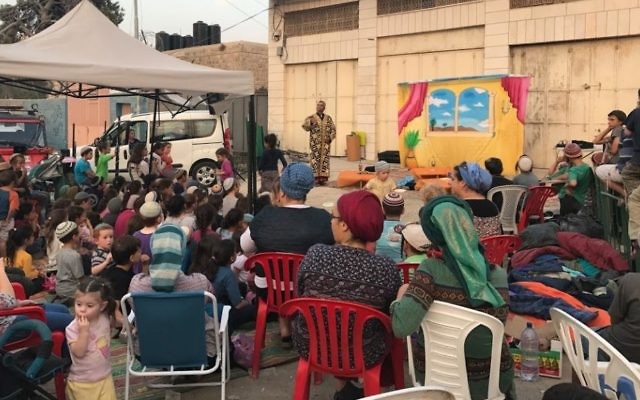 Young squatters of the Machpela House in Hebron watch a play outside the building on July 26, 2017. (Jacob Magid)