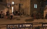 Squatters of the Machpela House in Hebron sit outside the building as Border Police look on, July  26, 2017. (Jacob Magid/Times of Israel)