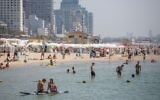 Israelis and tourists enjoy the beach in Tel Aviv, on a hot summer day, July 3, 2017. A new survey finds that they are optimistic and largely satisfied with their lives. (Miriam Alster/ FLASH90)