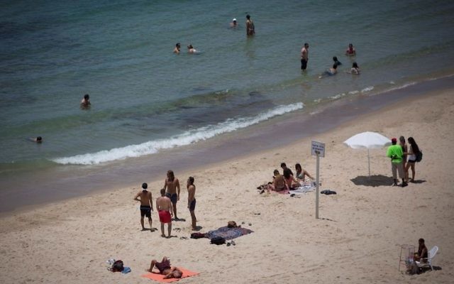People enjoy the beach in Tel Aviv on a warm summer day on July 4, 2017. (Miriam Alster/Flash90)