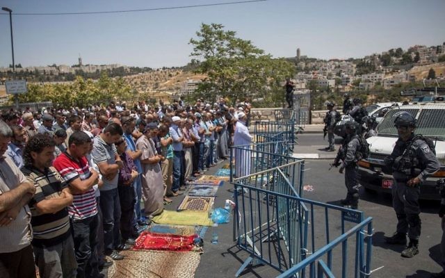 Muslims pray as Border Police officers stand guard during Friday prayers in the East Jerusalem neighborhood of Wadi Joz, July 14, 2017. (Yonatan Sindel/Flash90) Muslims pray as Border Police officers stand guard during Friday prayers in the East Jerusalem neighborhood of Wadi Joz, July 14, 2017. (Yonatan Sindel/Flash90)