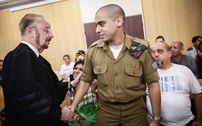 Elor Azaria shake hands with his attorney Yoram Sheftel before the start of a court hearing at the IDF's Tel Aviv headquarters on July 17, 2017. (Miriam Alster/Flash90)