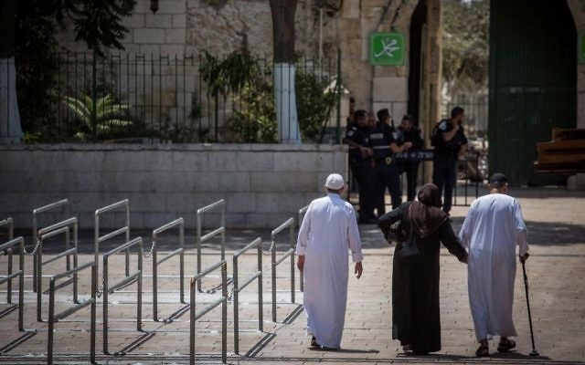 Police officers guard at an entrance to the Temple Mount, as a group of Muslims walk by metal railings installed at the site after a recent terror attack on July 25, 2017. (Hadas Parush/Flash90)