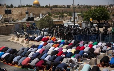 Muslim Palestinians pray as Israeli policemen stand guard during Friday prayers in the East Jerusalem neighborhood of Ras el Amud, outside the Old City, July 28, 2017 (Hadas Parush/Flash90)