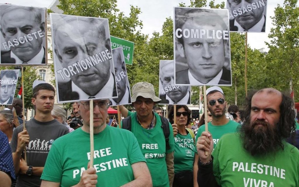 Pro-Palestinian activists hold pictures of Prime Minister Benjamin Netanyahu and French President Emmanuel Macron as they gather to protest Netanyahu's visit to France, July 15, 2017. (AP Photo/Michel Euler)