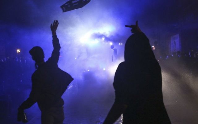 In this July 6, 2017 photo protesters are silhouetted against a water cannon of the police during violent demonstrations on the eve of the G-20 summit in Hamburg, northern Germany. The leader of the group of 20 meet Friday and Saturday in Hamburg. (Bodo Marks/dpa via AP)