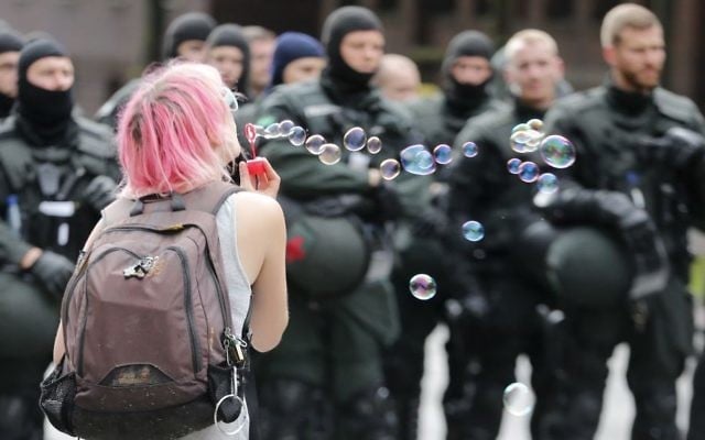 A protester blows soap bubbles in front of riot police during a protest on the second day of the G-20 summit in Hamburg, Germany on July 8, 2017. (AP/Michael Probst)