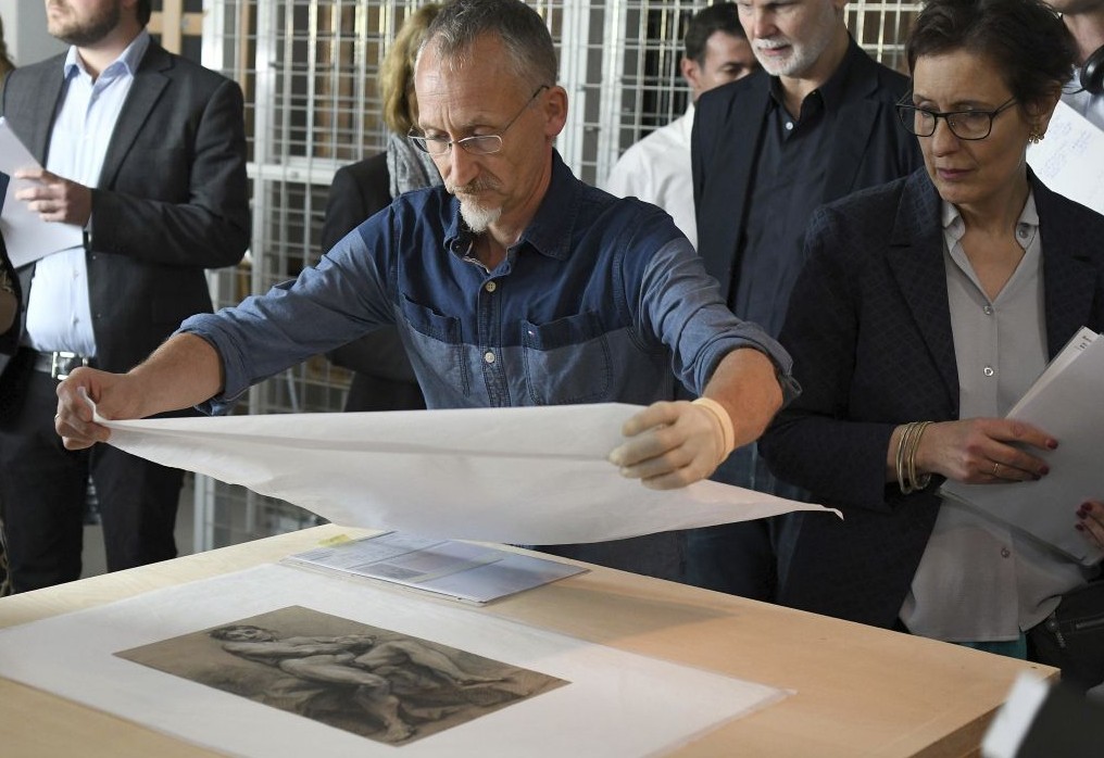 An employee covers the artwork 'Maennlicher Akt' (lit. 'Male Nude') by Francois Boucher (1703-1770) during a press talk on the preparations of an exhibition of exemplary works from the art collection of Cornelius Gurlitt discovered in 2012, in Bonn, Germany, Tuesday June, 27, 2017. (Henning Kaiser/dpa via AP)