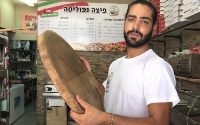 Shlomi Madar with the wooden pizza pie tray similar to the one he used to fend off a Palestinian terrorist who tried to stab him in his pizza kiosk in Petah Tikva, July 24, 2017. (Jacob Magid) Shlomi Madar with the wooden pizza pie tray similar to the one he used to fend off a Palestinian terrorist who tried to stab him in his pizza kiosk in Petah Tikva, July 24, 2017. (Jacob Magid)