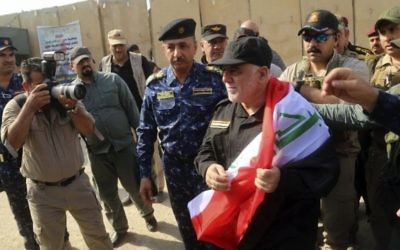 Iraq's Prime Minister Haider al-Abadi, center, holds a national flag upon his arrival to Mosul, Iraq, Sunday, July 9, 2017. Backed by the US-led coalition, Iraq launched the operation to retake Mosul from Islamic State militants in October. (Iraqi Federal Police Press Office via AP)