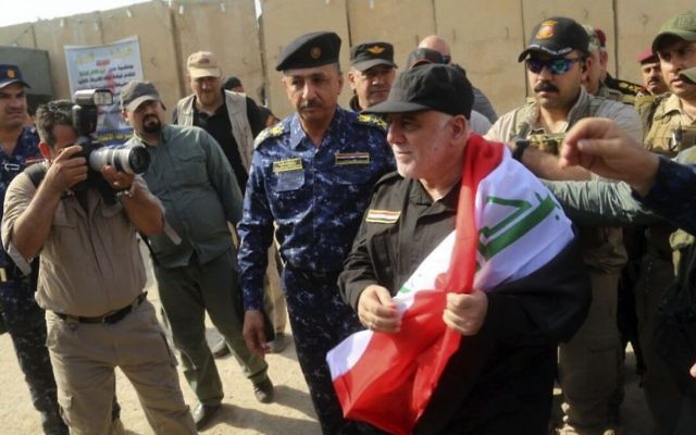 Iraq's Prime Minister Haider al-Abadi, center, holds a national flag upon his arrival to Mosul, Iraq, Sunday, July 9, 2017. Backed by the US-led coalition, Iraq launched the operation to retake Mosul from Islamic State militants in October. (Iraqi Federal Police Press Office via AP) Iraq's Prime Minister Haider al-Abadi, center, holds a national flag upon his arrival to Mosul, Iraq, Sunday, July 9, 2017. Backed by the US-led coalition, Iraq launched the operation to retake Mosul from Islamic State militants in October. (Iraqi Federal Police Press Office via AP)