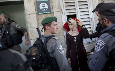Border Police officers stop a Palestinian woman for a security check as Palestinians gather for prayer at the Lions Gate, following an appeal from clerics for Muslims to pray in the streets instead of the Al-Aqsa Mosque compound on the Temple Mount, in Jerusalem's Old City, Wednesday, July 19, 2017. (AP Photo/Oded Balilty)