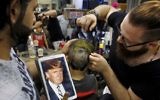 In this Friday, July 14, 2017 photo, Muhannad Khaled Omar, right, prepares an image of US President Donald Trump on the back of a customer's head at his barber shop in Burj al-Barajneh, southern Beirut, Lebanon. (AP Photo/Bilal Hussein)