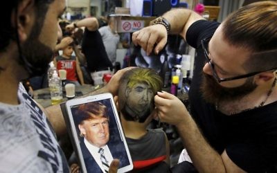 In this Friday, July 14, 2017 photo, Muhannad Khaled Omar, right, prepares an image of US President Donald Trump on the back of a customer's head at his barber shop in Burj al-Barajneh, southern Beirut, Lebanon. (AP Photo/Bilal Hussein)