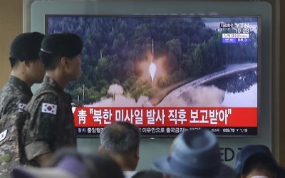 Army soldiers walk by a TV news program showing a file image of a missile being test-launched by North Korea at the Seoul Railway Station in Seoul, South Korea, Tuesday, July 4, 2017 (AP Photo/Ahn Young-joon)