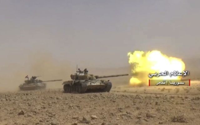 This frame grab from video released on May 24, 2017 and provided by the government-controlled Syrian Central Military Media, shows a Syrian forces tank firing at Islamic States positions in Homs province, Syria (Syrian Central Military Media, via AP)