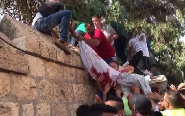 Screenshot from footage posted on Palestinian media showing what appears to be a body of a protester covered in a bloodied sheet being carried over a wall in East Jerusalem after being taken from the hospital July 22, 2017. (Screenshot/Ma'an) Screenshot from footage posted on Palestinian media showing what appears to be a body of a protester covered in a bloodied sheet being carried over a wall in East Jerusalem after being taken from the hospital July 22, 2017. (Screenshot/Ma'an)
